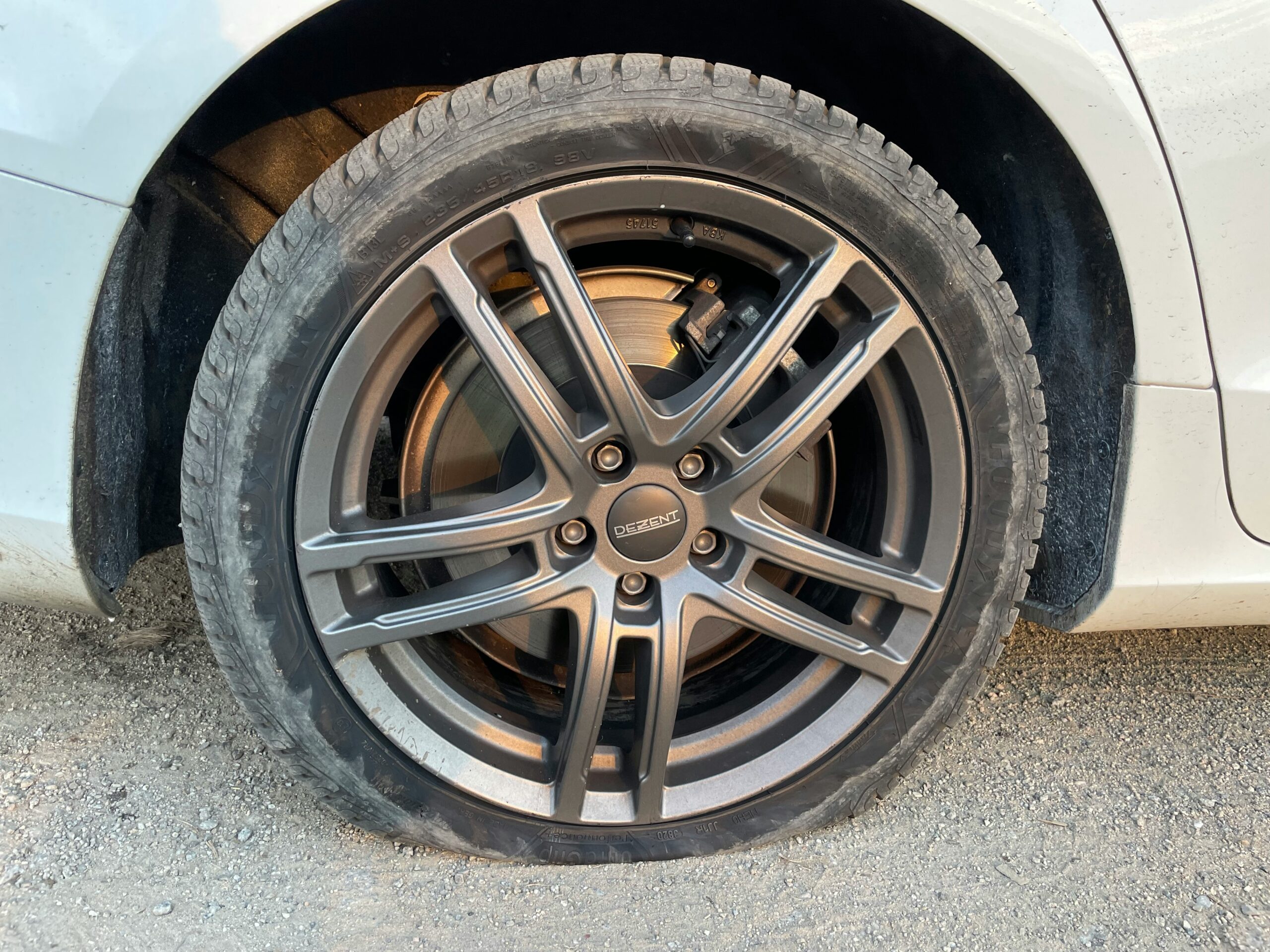 Image of a flat tyre on a car with a grey five-spoke alloy wheel.