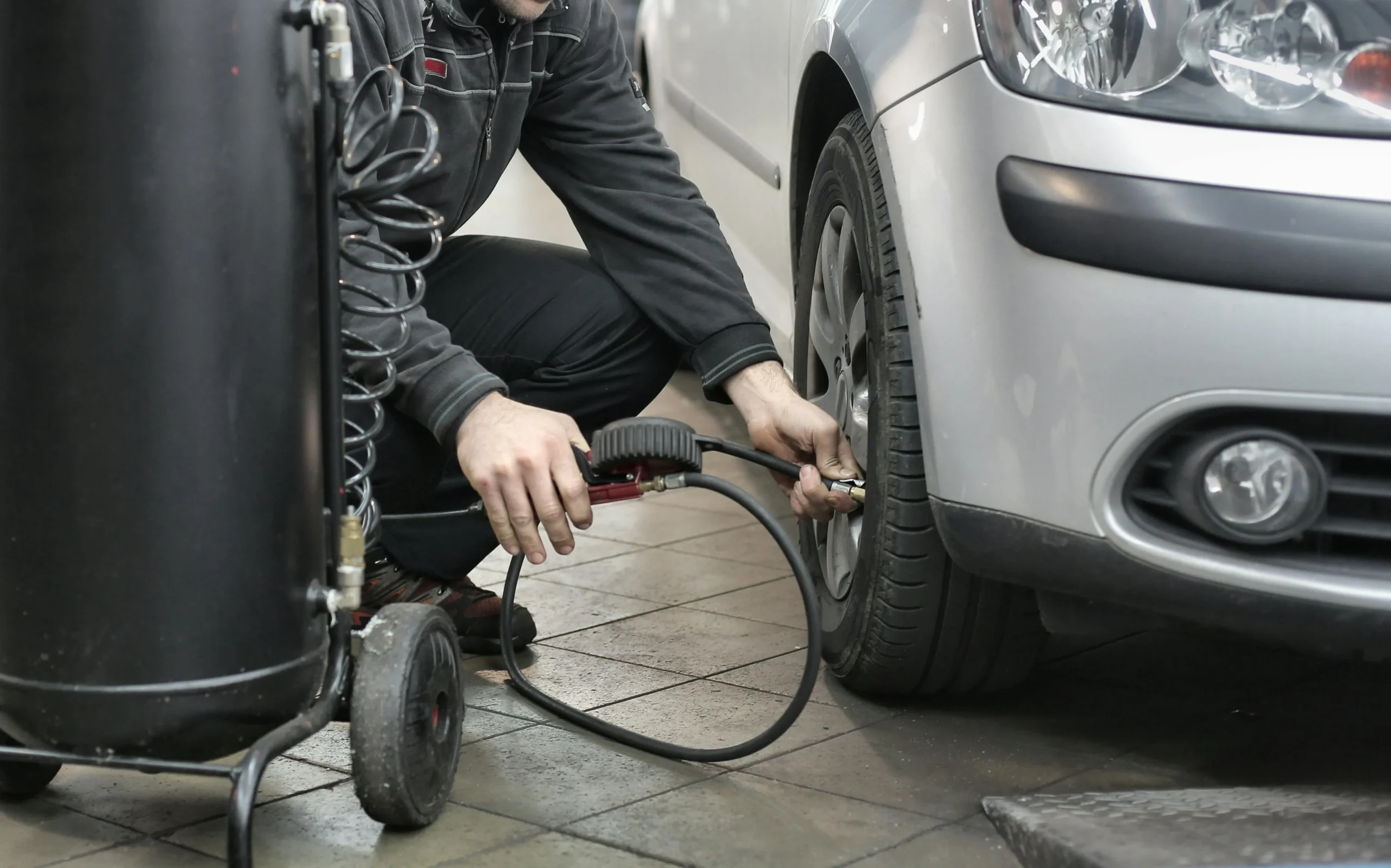 A man using machine to sort the tyre pressure of a car.